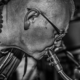 Close-up black and white portrait of a musician playing a saxophone passionately.