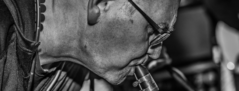 Close-up black and white portrait of a musician playing a saxophone passionately.
