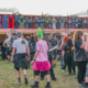 Festivalgoers browsing official band merchandise at Bloodstock Open Air 2025, crowd gathered in front of metal festival merch stalls