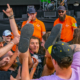 Crowd surfer being supported by fans and watched by event security in orange shirts during Shrapnel’s set at Bloodstock Open Air Festival